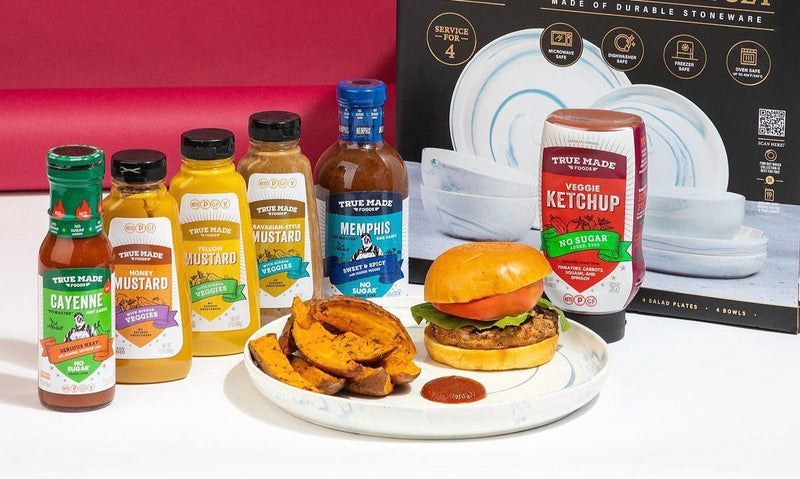 True Made Foods’ hot sauce, mustards, BBQ sauce, and ketchup bottles next to a burger meal and a dinnerware set box.