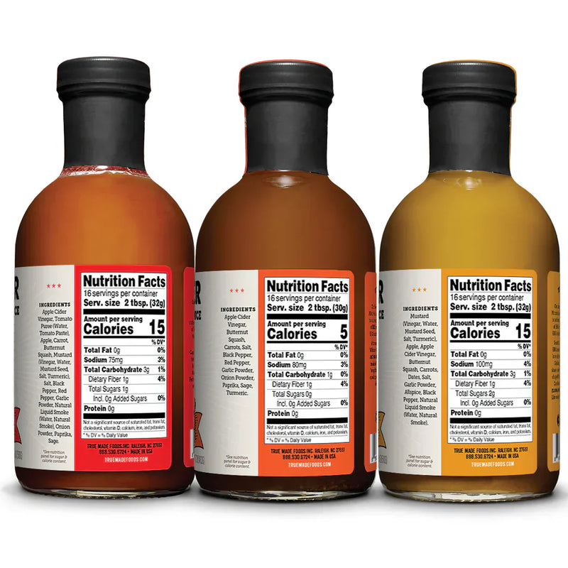 Nutrition Facts and ingredient labels displayed on the back of three True Made Foods BBQ sauce bottles, highlighting no-added-sugar ingredients and nutritional information.
