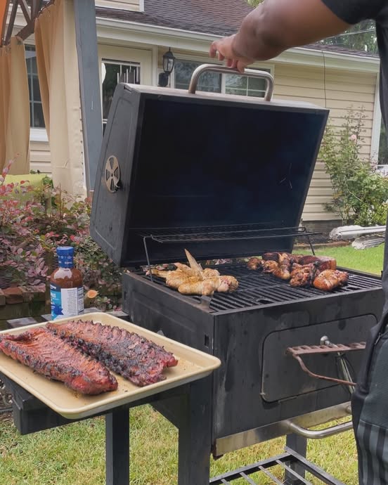 Tray of grilled ribs beside chicken on a backyard BBQ grill with True Made Foods Memphis BBQ sauce.
